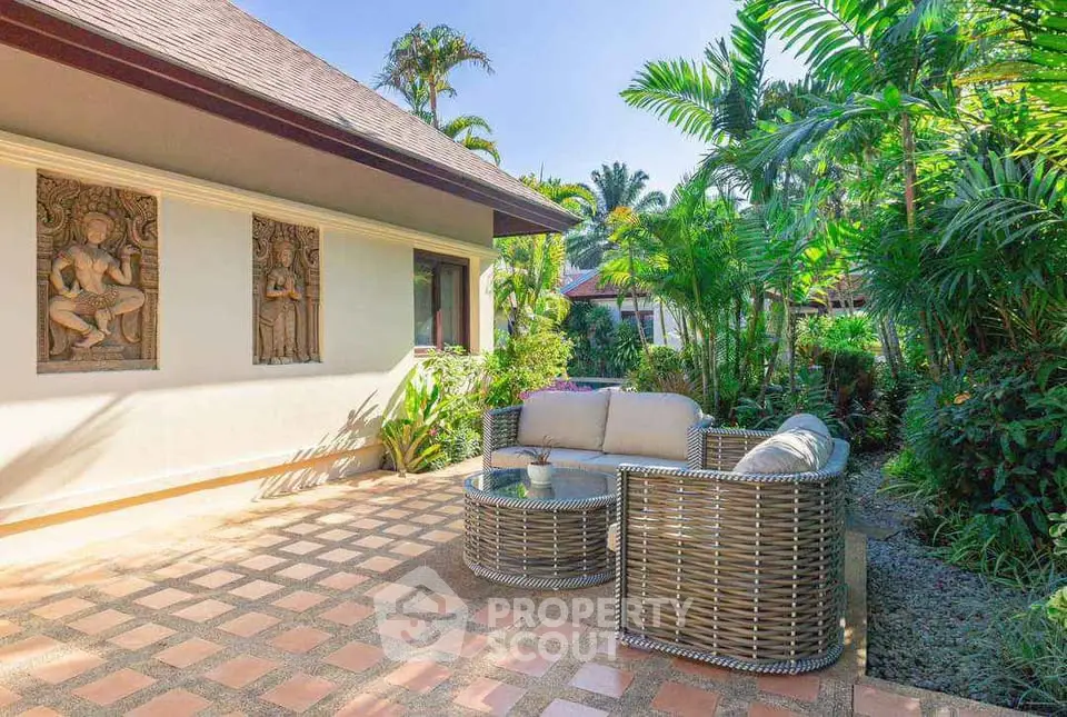 Tropical garden patio with stylish wicker furniture and lush greenery, perfect for outdoor relaxation.