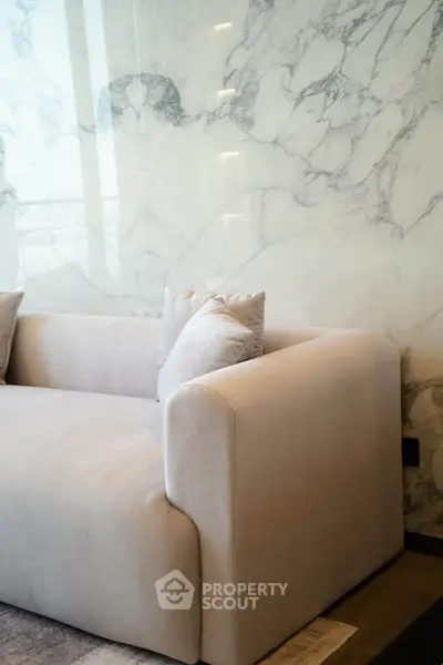 Luxurious living room with elegant marble wall and plush beige sofa, perfect for modern interiors.