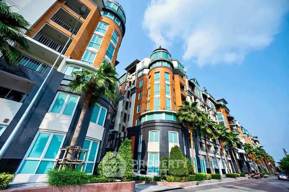 Modern multi-story residential building with vibrant facade and lush landscaping.