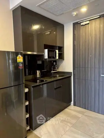 Modern compact kitchen with sleek cabinetry and built-in microwave in urban apartment.