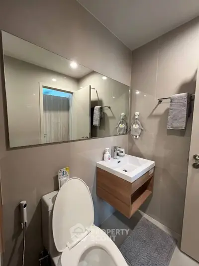 Modern bathroom with sleek fixtures and large mirror in a contemporary apartment.