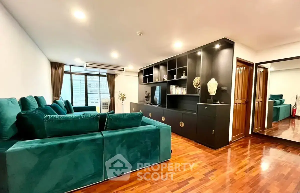Spacious living room with elegant green sofa and wooden flooring