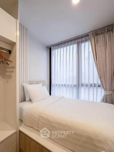 Cozy modern bedroom with large window and elegant curtains, perfect for relaxation.