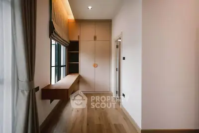 Modern study room with wooden flooring and built-in storage in a bright apartment.