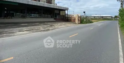 Street view of commercial building with spacious parking area and clear road access.