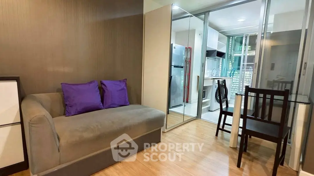 Modern apartment living room with cozy sofa and sleek kitchen area.