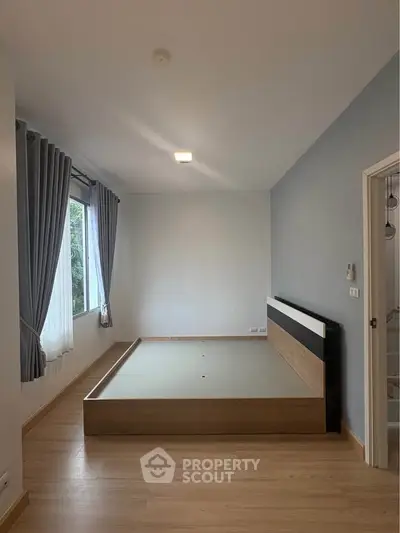 Spacious bedroom with modern bed frame and large window for natural light.