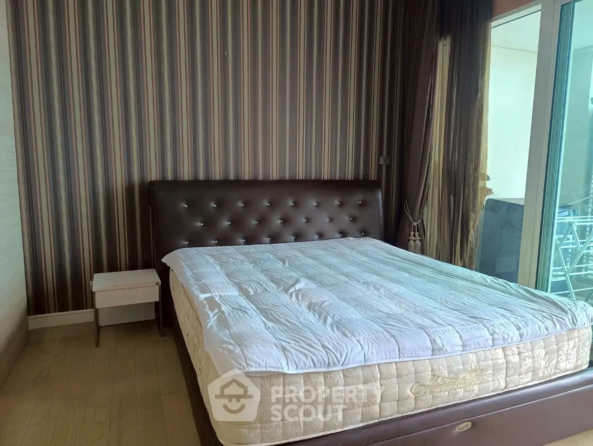 Spacious bedroom with modern decor and large windows offering natural light.