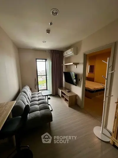 Modern living room with sofa, TV, and balcony view in cozy apartment