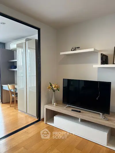 Modern living room with sleek TV setup and sliding glass door to study area.