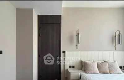 Modern bedroom with stylish wall sconces and cozy pillows on a sleek bed.