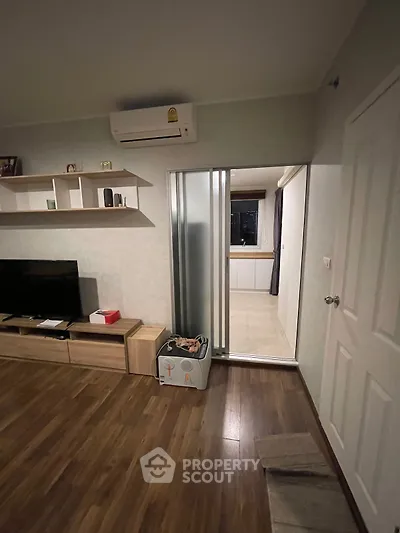 Modern living room with wooden flooring, air conditioning, and sliding door to adjacent room.
