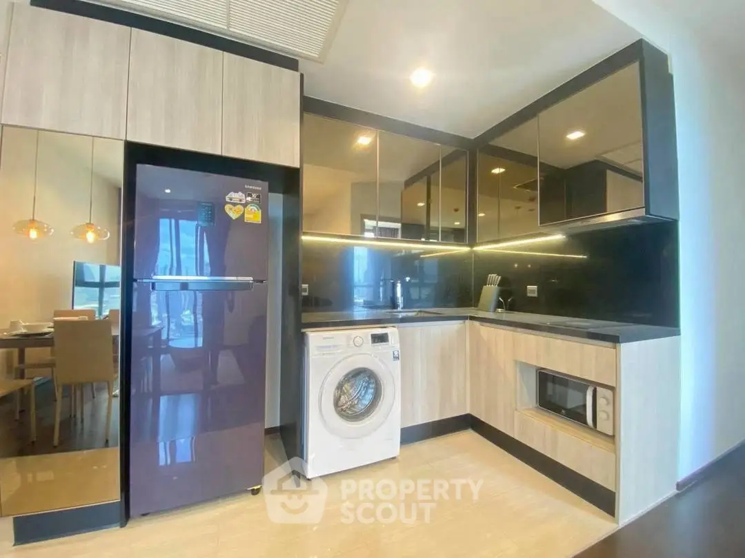 Modern kitchen with sleek cabinets, washing machine, and dining area view.