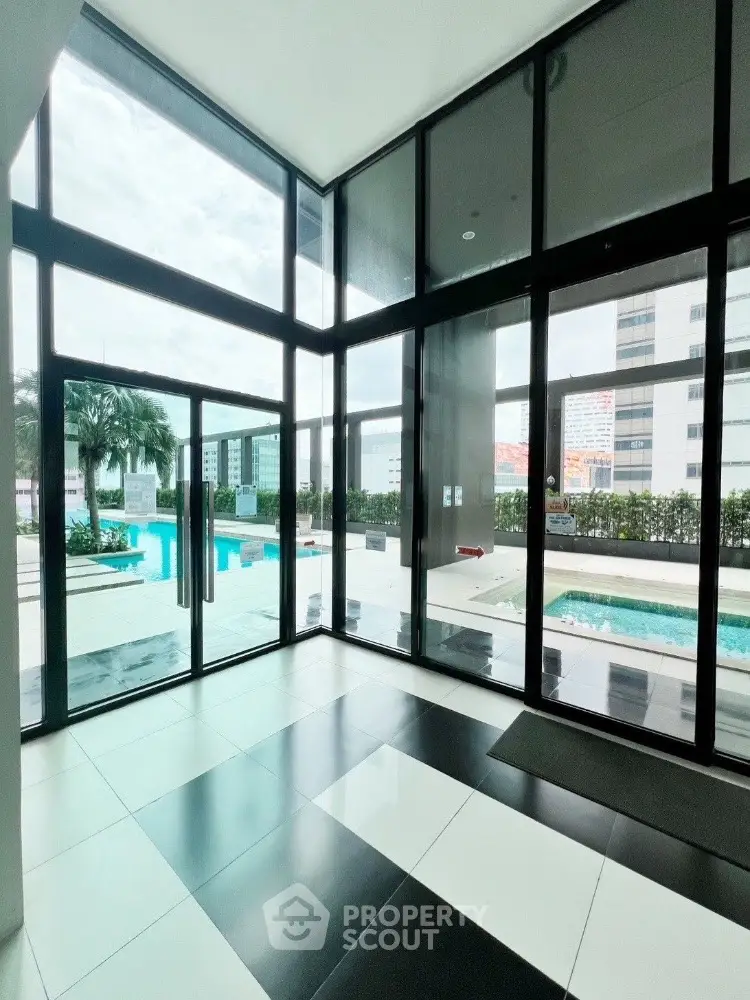 Luxurious modern building entrance with pool view and floor-to-ceiling windows