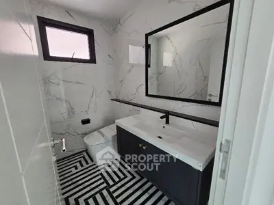 Modern bathroom with stylish black and white design, featuring a sleek vanity and large mirror.