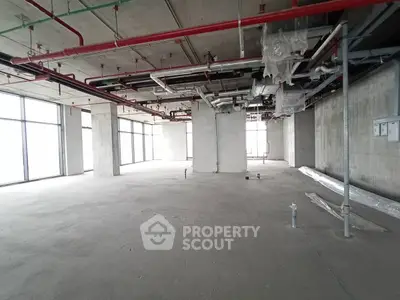 Spacious unfinished commercial space with large windows and exposed ceiling pipes.