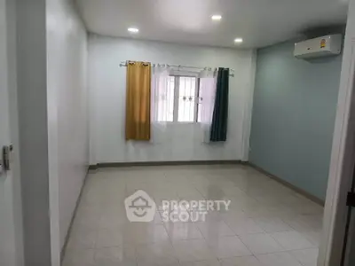 Spacious empty room with tiled floor and colorful curtains, ideal for customization.