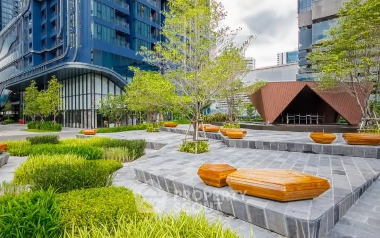 Modern urban garden with stylish seating and lush greenery in a contemporary building complex.