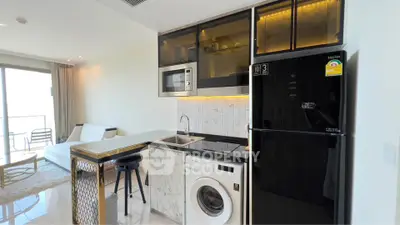 Modern studio apartment with sleek kitchen and washing machine, featuring open layout and stylish decor.