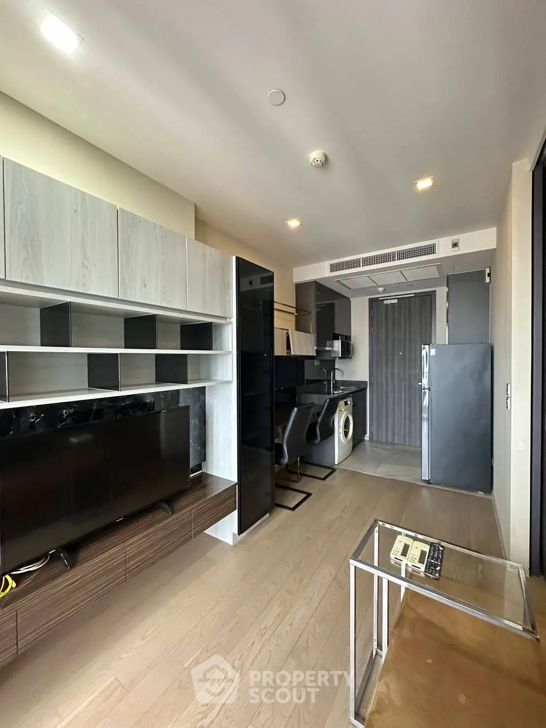 Modern living room with sleek furniture and open kitchen layout in a stylish apartment.