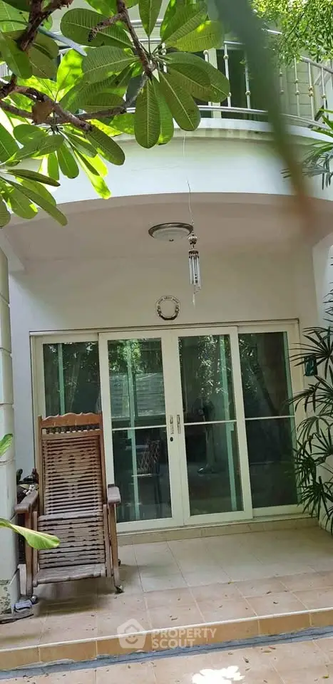 Charming garden view entrance with sliding glass doors and cozy rocking chair.