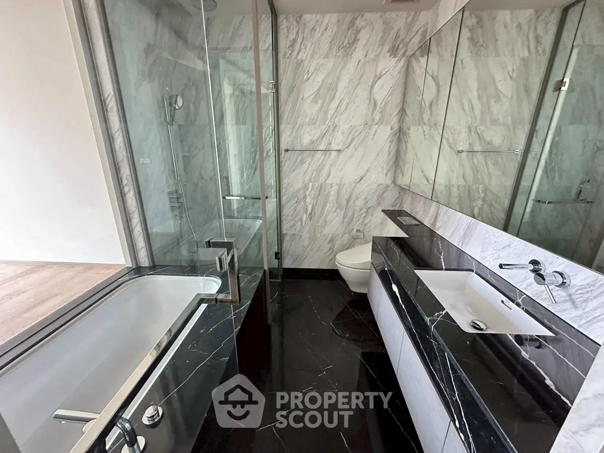 Luxurious marble bathroom with sleek black and white design, featuring a modern bathtub and glass shower.