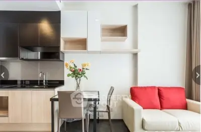 Modern living room with open kitchen, featuring sleek cabinetry and cozy seating area.