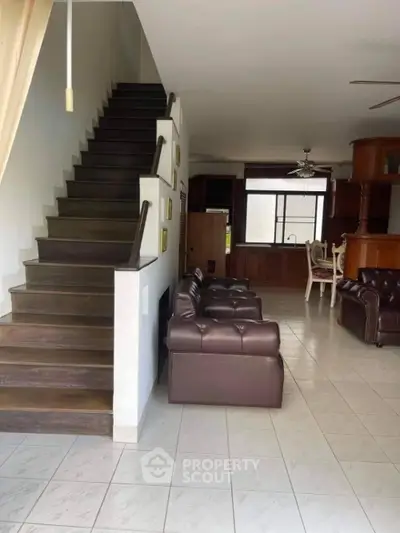 Spacious living room with elegant staircase and leather sofas in a modern home.