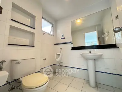 Spacious bathroom with modern fixtures and large mirror in a bright, tiled setting.