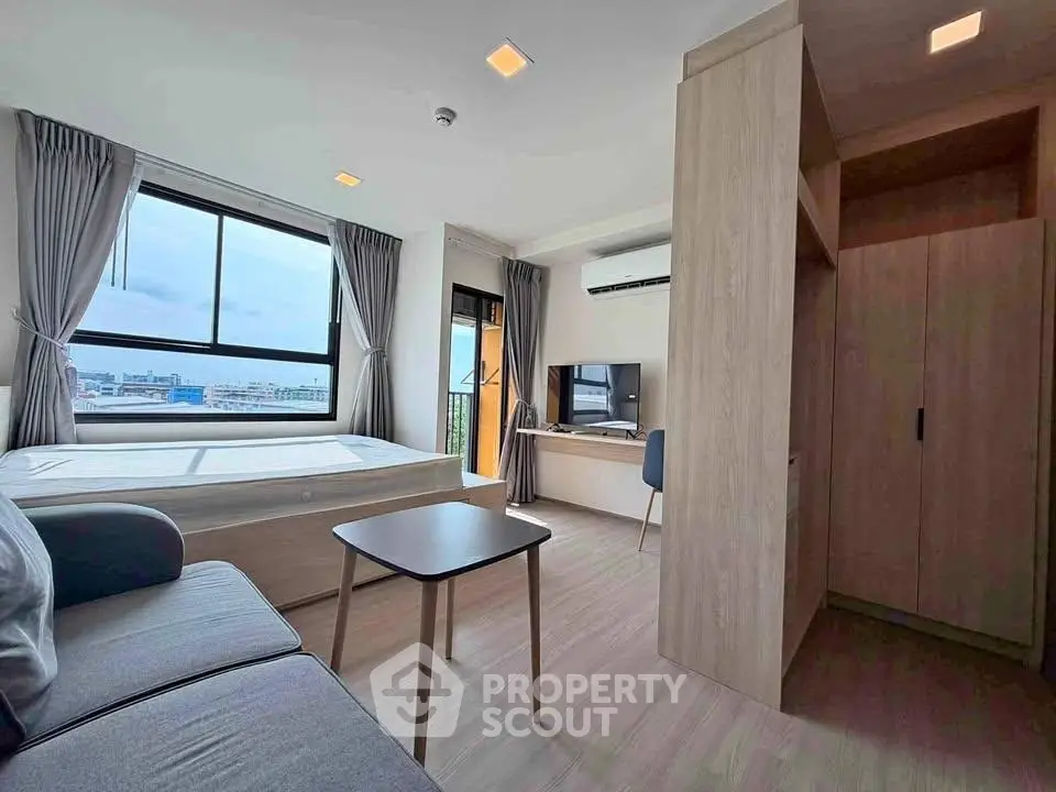 Modern studio apartment with large windows and stylish furnishings, offering a bright and cozy living space.