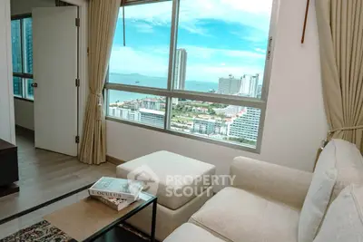 Modern living room with stunning city and ocean view from large window, featuring cozy seating and elegant decor.