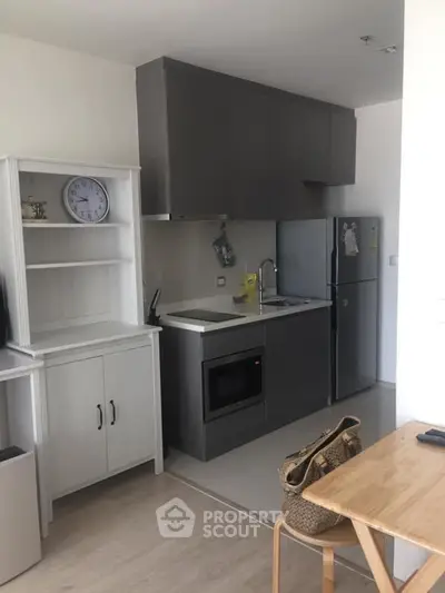 Modern kitchen with sleek cabinets, stainless steel fridge, and built-in oven in a cozy apartment.