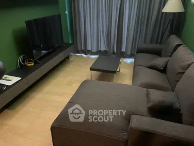 Cozy living room with modern gray sofa and large TV, perfect for relaxation.