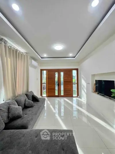 Spacious modern living room with elegant gray sofa and large windows.