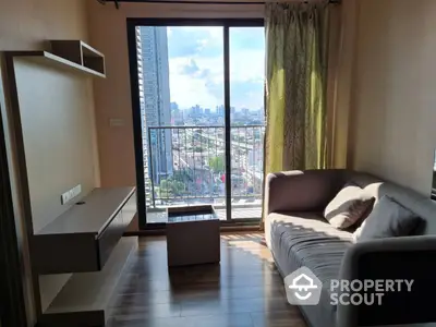 Sunlit living room with a plush sofa, modern furniture, and a captivating city view through the large glass window, perfect for urban living.