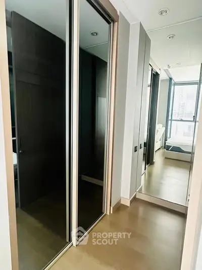 Modern bedroom with mirrored closet doors and city view window.