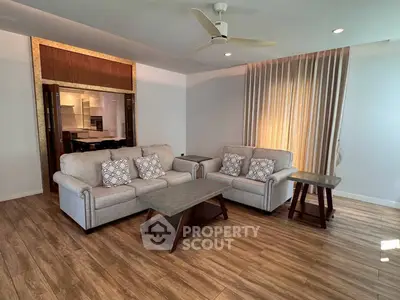 Spacious living room with elegant decor and wooden flooring, featuring comfortable sofas and modern lighting.