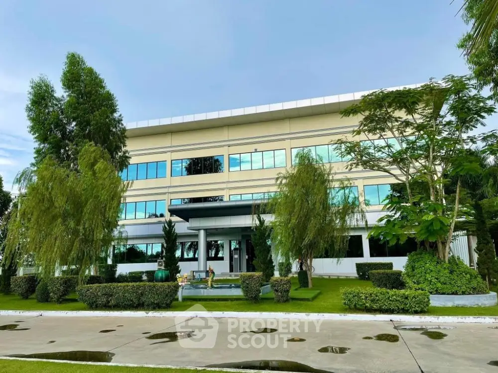 Modern commercial building exterior with lush green landscaping and expansive glass facade offering a professional corporate environment.