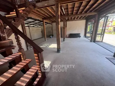 Spacious open-plan interior with wooden beams and staircase, perfect for rustic charm lovers.