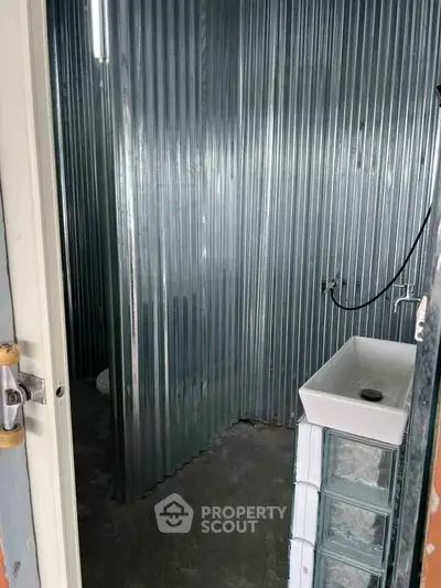 Industrial-style bathroom with corrugated metal walls and modern sink design.