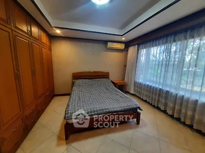 Spacious bedroom with large window and built-in wooden wardrobe