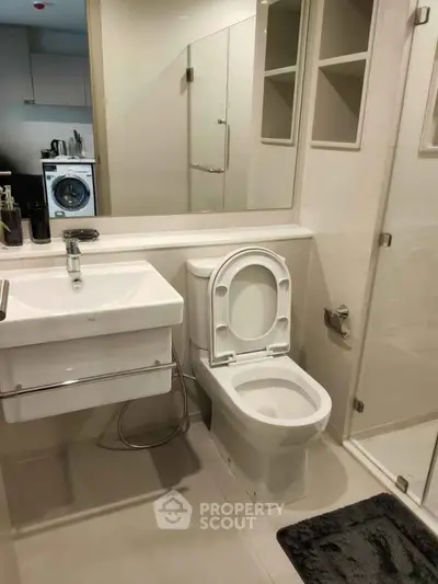 Modern bathroom with sleek fixtures and washing machine in compact layout.