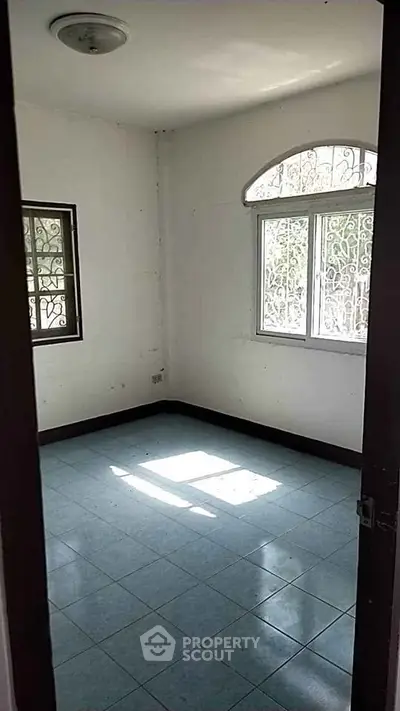 Bright empty room with tiled floor and barred windows, ideal for customization.
