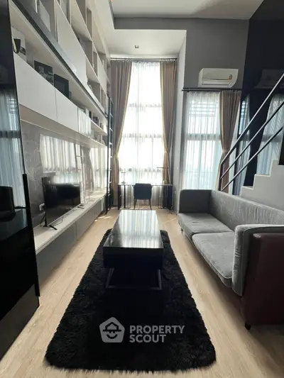 Modern living room with high ceilings, large windows, and stylish furniture