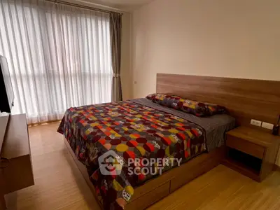 Cozy bedroom with modern wooden furniture and large window for natural light.