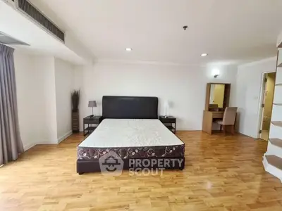 Spacious bedroom with wooden flooring and modern furnishings in a luxury apartment.