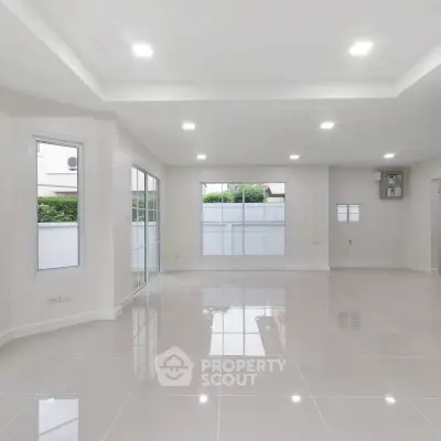 Spacious modern living room with large windows and glossy tiled floors.