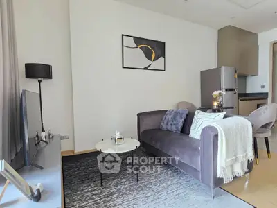 Modern living room with stylish decor and open kitchen layout, featuring a cozy sofa and elegant furnishings.