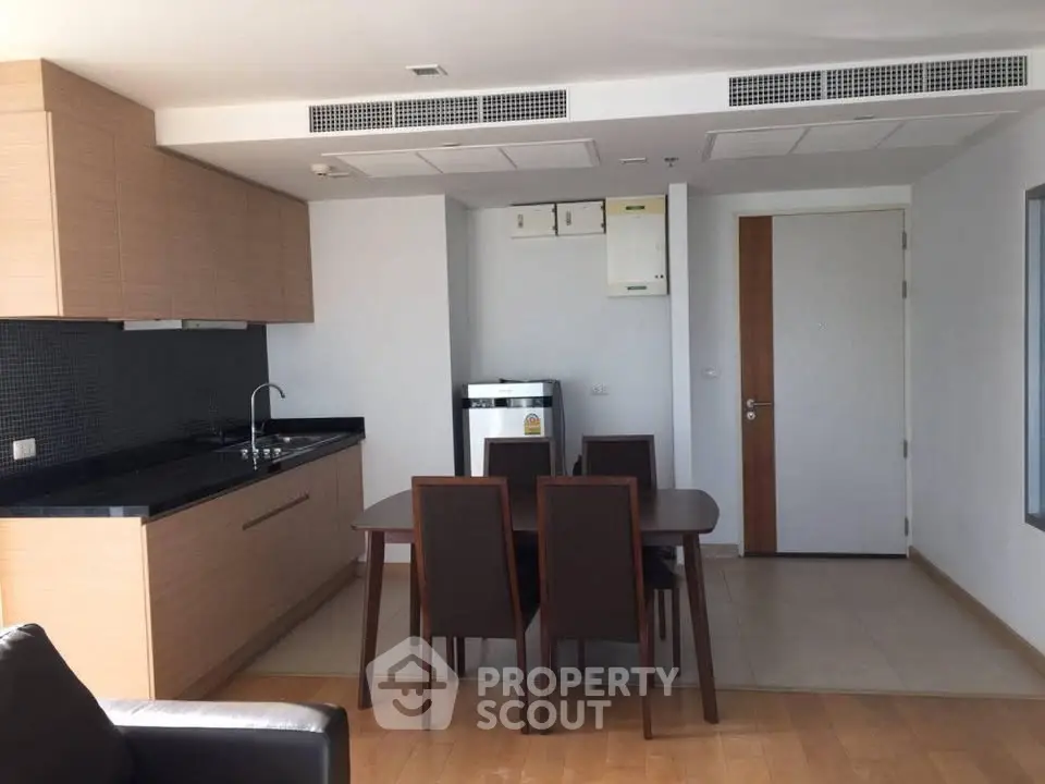 Modern kitchen and dining area with sleek cabinetry and integrated appliances in a stylish apartment.
