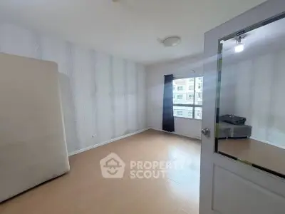 Spacious empty room with large window and wooden flooring in modern apartment.
